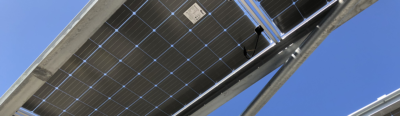 Närbild på solceller monterade på en grå ställning mot en klarblå himmel