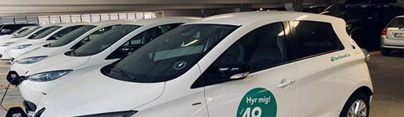 Vita bilpoolsbilar från OurGreenCar som är parkerade i P-huset