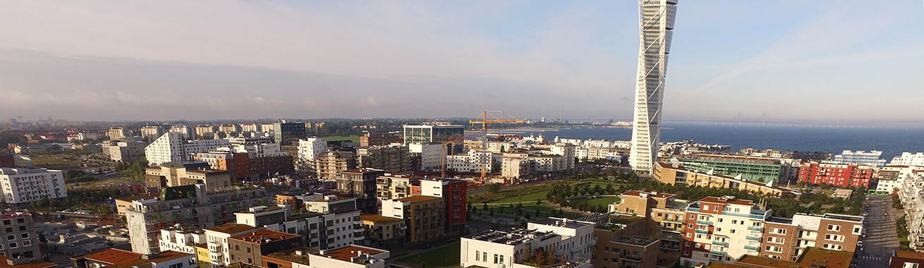 Översiktsbild över delar av Malmö med Turning Torso i mitten och kustremsan med vatten i bakgrunden