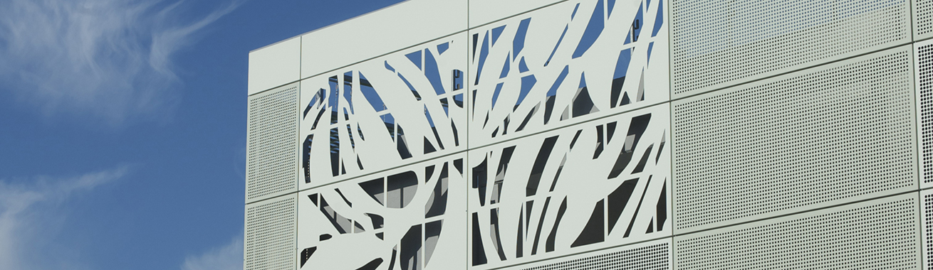 Närbild på P-huset Stadions fasad i ljus färg med blå himmel