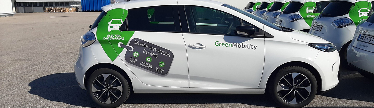Vit bil med GreenMobilitys logotyp och användningsinstruktioner i grönt och grått