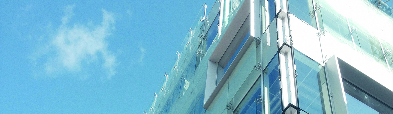 Närbild på en fasad i vitt och glas med en blå himmel